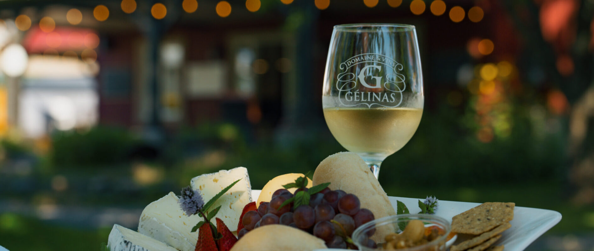 Vin blanc du Domaine Gélinas accompagné d'une assiette de fromages et de fruits.