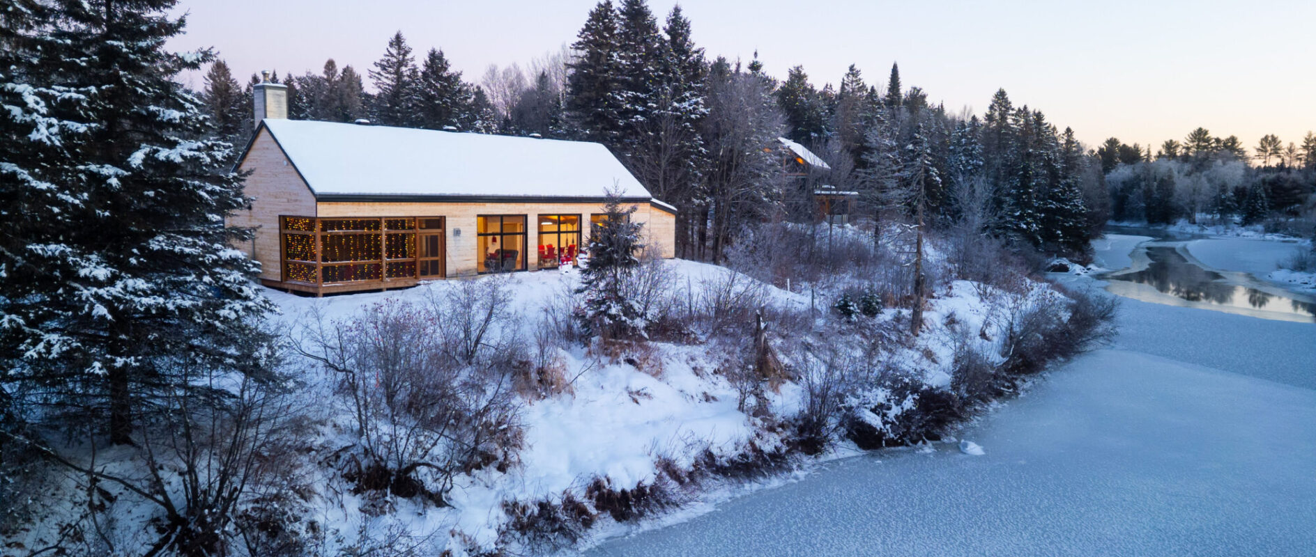 Chalet enneigé le Payageur sur le bord d'une rivière au Baluchon