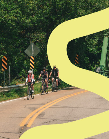 Trois cyclistes sur une route de campagne en Mauricie lors d'une journée ensoleillée d'été en Mauricie