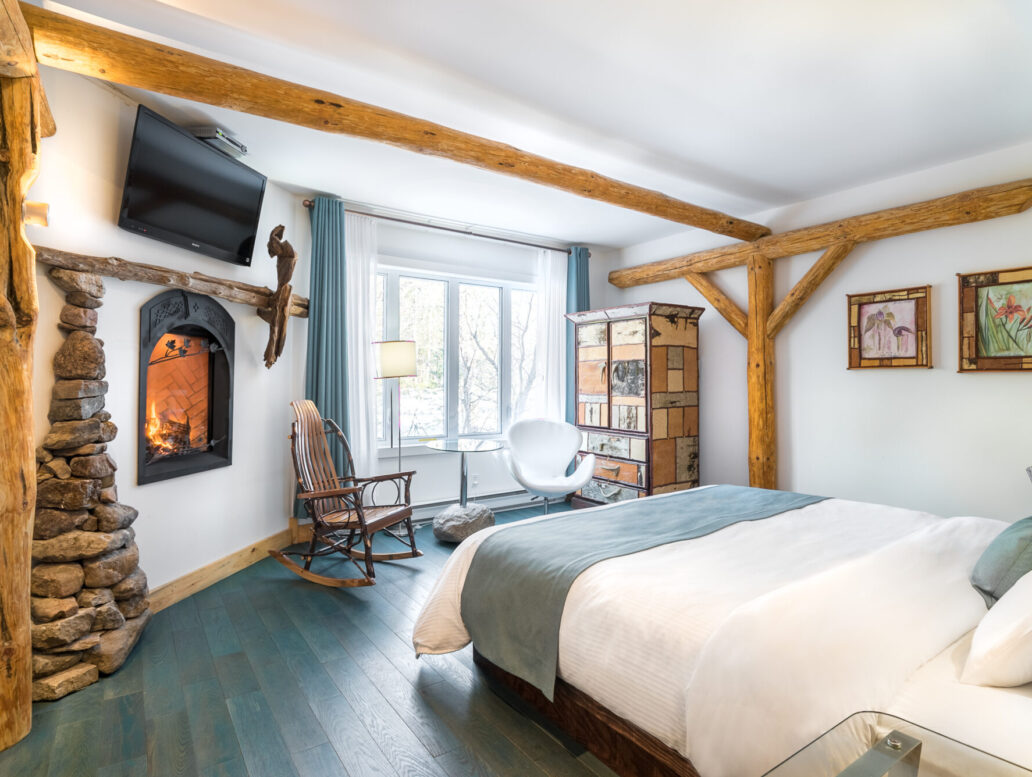 Chambre avec lit queen et foyer en auberge au Baluchon Éco-villégiature