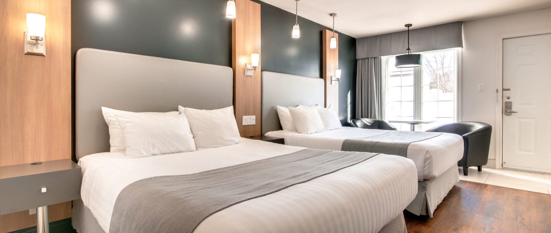 Chambre de l'Hôtel Marineau avec deux lits queen et porte donnant accès à l'extérieur.