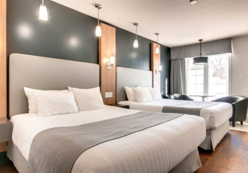 Chambre de l'Hôtel Marineau avec deux lits queen et porte donnant accès à l'extérieur.